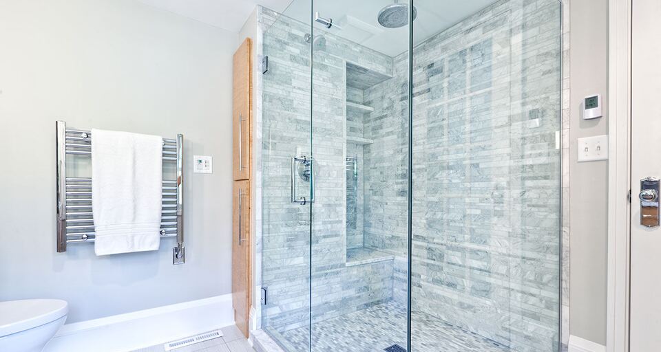 Frameless corner glass shower with gray stone tile and chrome hardware