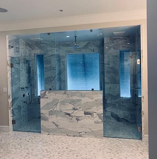 Large double-entry frameless glass shower with a marble half wall