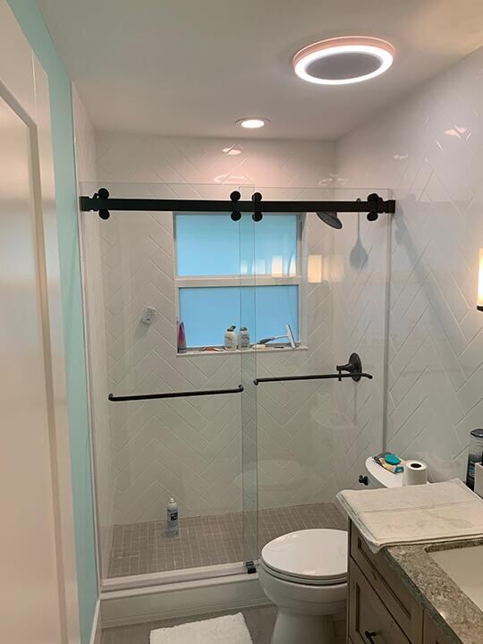 Frameless sliding shower door with matte black roller hardware