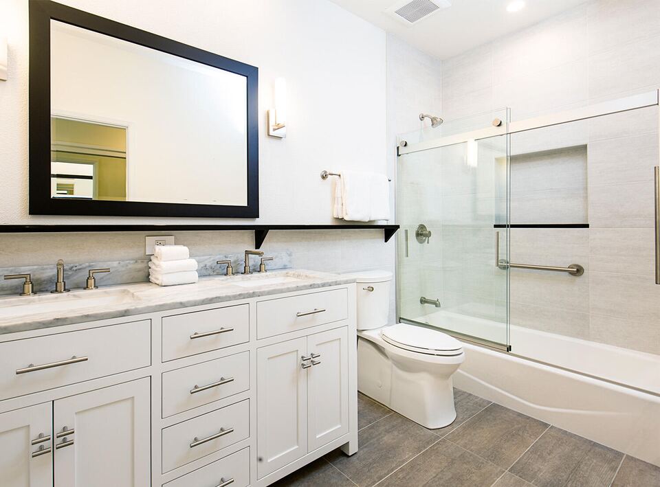 Bathroom with sliding glass tub doors, a white vanity and a black-framed mirror
